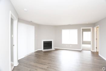 A spacious living room with a fireplace and hardwood floors.